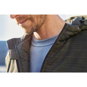 A close-up of a man wearing a men's padded hybrid jacket in earthy tones, featuring a hood and textured fabric.