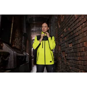 A high-visibility work jacket in yellow and black with a logo, set against a textured brick background.