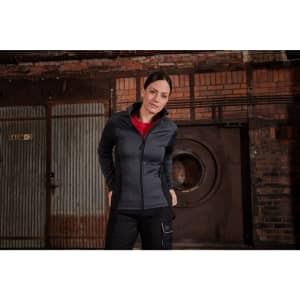 A stretch fleece jacket in dark grey, featuring a zippered front and a collar, displayed in an industrial setting.