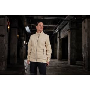 A cream Sherpa jacket with a full zip and side pockets is displayed in an industrial setting.