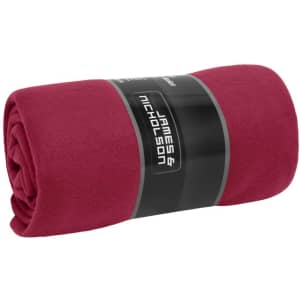 A rolled-up fleece blanket in a rich burgundy colour, featuring a logo on the packaging.
