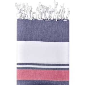 A striped beach blanket featuring navy blue, white, and red colours, with a fringed edge. It has a logo.