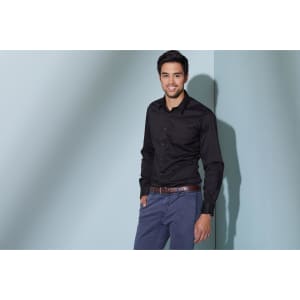 A long-sleeve button-up shirt in black, worn by a man with a relaxed pose against a light blue background.