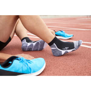 Sport sneaker socks in black and grey, paired with blue athletic shoes, displayed on a track surface.
