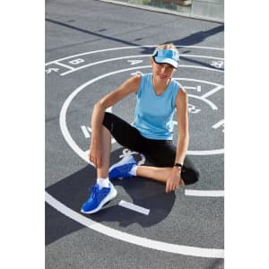 A blue ladies running tank top worn with black leggings, featuring a logo, against a patterned sports surface.