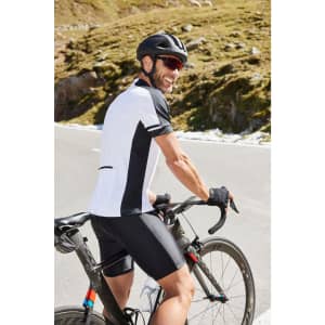 A man wearing a black and white cycling shirt with a helmet, riding a bicycle on a scenic mountain road.