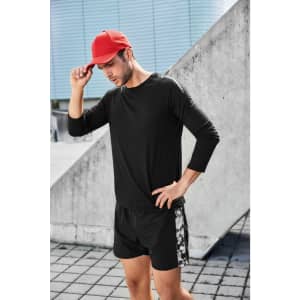 A man wearing a black long-sleeve sports shirt and shorts, complemented by a red cap, poses outdoors.