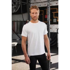 Men's sports shirt in white, featuring a logo, styled with black athletic leggings in a gym setting.