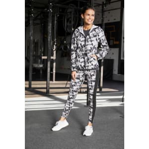 A ladies’ sports jacket in a black and grey abstract pattern, featuring a logo, paired with matching leggings.