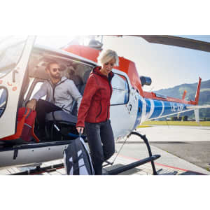 A red hoodie worn by a woman exiting a helicopter, accompanied by a man in a light-coloured hoodie.