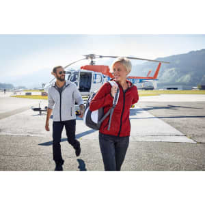 A grey and a red men's knitted fleece hoodie are worn by two people near a helicopter on a tarmac.