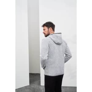A grey knitted fleece hoodie with a hood, featuring a logo, worn by a man facing away from the camera.
