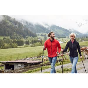 A red fleece jacket and a navy fleece jacket worn by a man and a woman walking in a scenic rural landscape.
