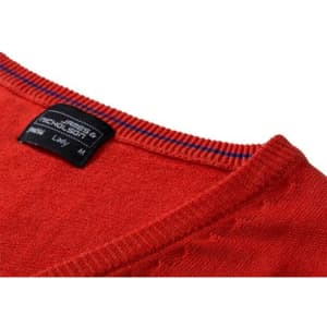 A red ladies v-neck vest made of knitted material, featuring a label and striped detailing around the neckline.
