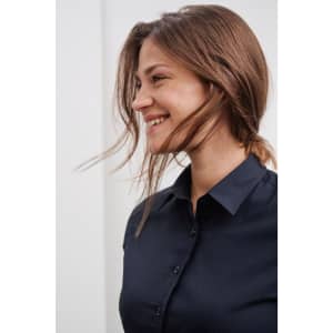 A navy button-up shirt with a sleek design, featuring a collar and buttons, worn by a smiling woman.