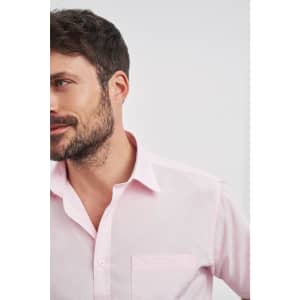 A pink button-up shirt with a chest pocket, featuring a sleek collar and a subtle logo.