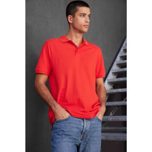 A men's polo shirt in vibrant red, featuring a collar and a logo, paired with casual denim jeans.