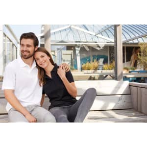 A black and a white ladies active polo shirt displayed on models in a casual outdoor setting. The shirts feature logos.