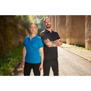 A blue polo shirt on a woman and a black polo shirt on a man, both with logos, posing outdoors.