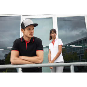 A black polo shirt with red accents worn by a man, alongside a woman in a white polo shirt with red details.
