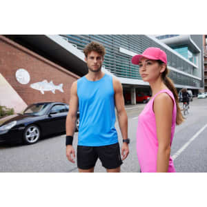 A blue men's active tank top and a pink women's tank top are modelled in an urban setting. Both feature logos.