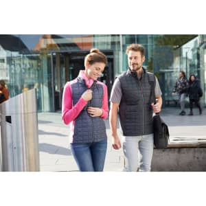 A grey knitted hybrid vest worn by two people, one in a pink top, walking in an urban setting.