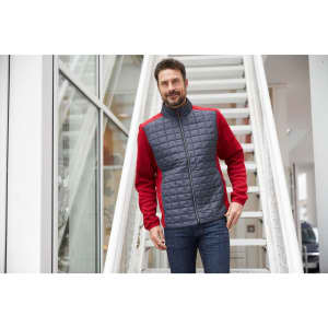 A knitted hybrid jacket featuring red sleeves and a grey quilted front, with a zippered closure and a logo.