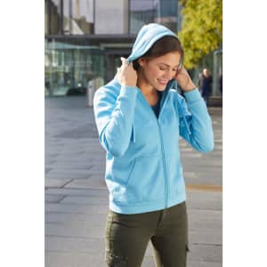 A blue zip-up hoodie with a hood, being worn by a woman outdoors. The hoodie features a logo.