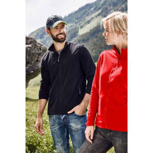 A couple stands outdoors wearing jackets; one in black and the other in red, with a logo on the jackets.