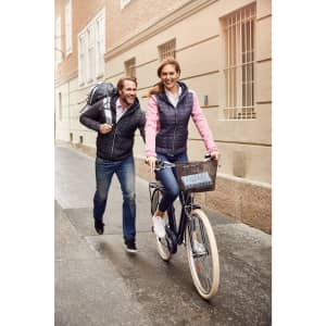 A ladies' knitted hybrid jacket in pink and grey, worn by a woman cycling, while a man walks alongside.