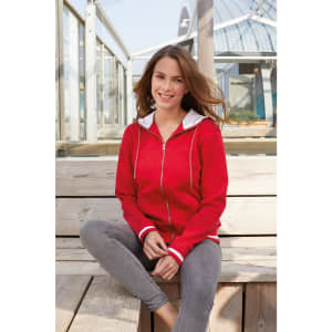 A red track jacket with white accents, featuring a zip front and a hood, worn by a woman sitting on a wooden bench.
