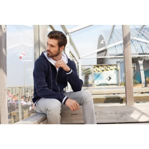 A navy blue men's track jacket with a hood, featuring a two-tone design, displayed in a bright outdoor setting.