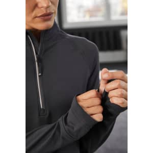 A close-up of a woman wearing a black half-zip sports shirt, showcasing the sleeves and zipper detail.