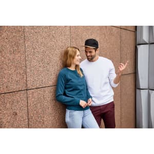 A teal jumper worn by a woman and a white jumper worn by a man, both smiling against a textured wall.