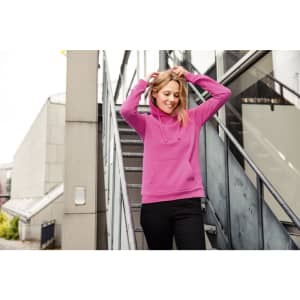 A pink ladies hoodie with a drawstring hood, worn by a woman, against an urban backdrop of stairs and buildings.