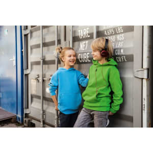A blue hoodie and a green hoodie worn by two children, standing next to a shipping container. The children are smiling and one is wearing headphones.