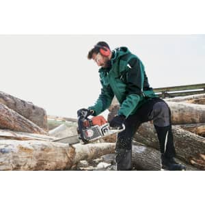 A green Craftsmen Softshell Jacket worn by a person using a chainsaw while cutting logs.