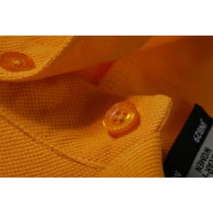 A close-up of an orange work polo shirt featuring a textured fabric and contrasting buttons.