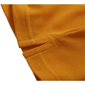 A close-up of an orange polo shirt fabric, highlighting stitching details and texture. The shirt features a logo.