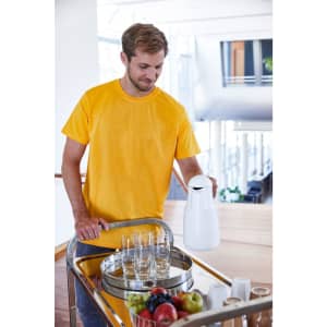 A man in a bright yellow workwear t-shirt is serving drinks from a tray with glasses and a jug.