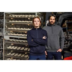 A navy half zip hoodie on a woman and a grey half zip hoodie on a man, both standing in a warehouse setting.