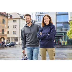 A grey half zip hoodie on a man and a navy hoodie on a woman, both in an urban setting.