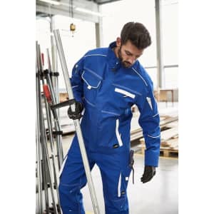 A blue workwear jacket with white accents, worn by a man in a workshop setting. The jacket features a logo.