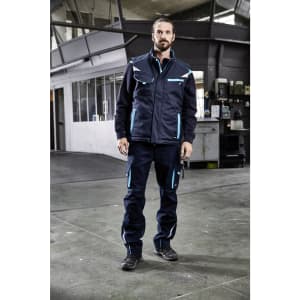 A padded work vest in navy blue with light blue accents, featuring pockets and a logo, worn by a person indoors.
