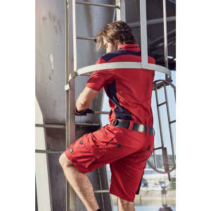A man climbs a ladder wearing a red and navy work polo shirt with matching red shorts. The shirt has a logo.