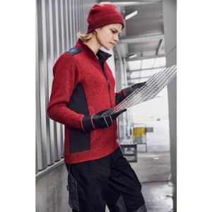 A red knitted fleece jacket with black accents, worn by a person reviewing documents in an industrial setting.