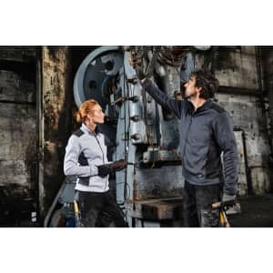 A grey fleece jacket worn by a woman, paired with a male model in a darker fleece jacket, both in an industrial setting.