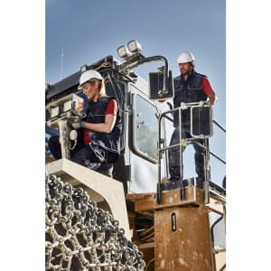 A padded softshell vest in navy, worn by workers on machinery, featuring a logo on the front.