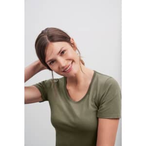 A woman in an olive green t-shirt smiles at the camera. The shirt has a fitted design and a round neckline.