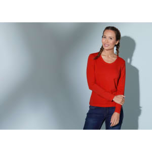 A red long-sleeve stretch shirt worn by a model, accompanied by blue jeans. The shirt has a logo.